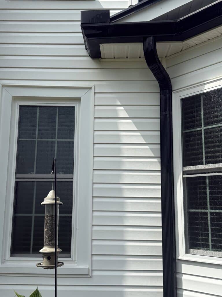 Brown runoff stains below gutter after soft washing